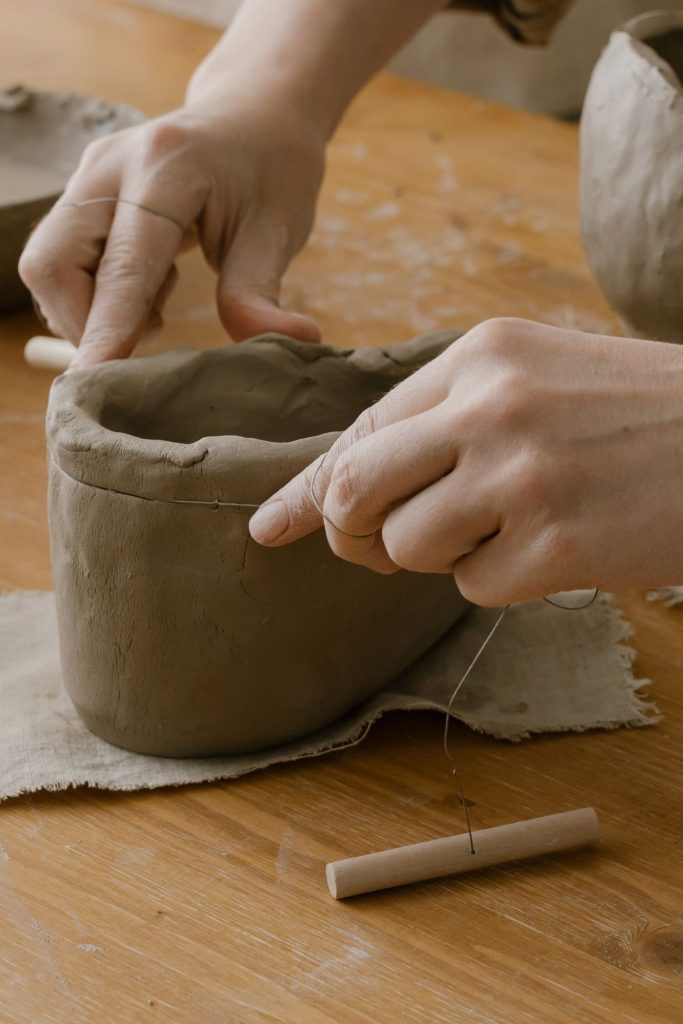 Handen, klei en gereedschap tijdens het maken van keramiek